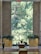 A serene interior space with a large window that showcases a lush, green view of trees outside. The room includes two large golden planters filled with vibrant greenery and flowers. There are small statues and more flowers placed near a small step or ledge. The floor features a polished stone surface with decorative rugs adding warmth to the space. An 'Exit' sign is visible at the top of the window structure.