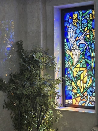 Bright window art featuring colorful birds and leaves, catching sunlight beautifully.