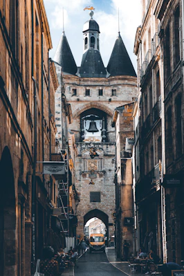 a narrow city street with a clock tower in the background