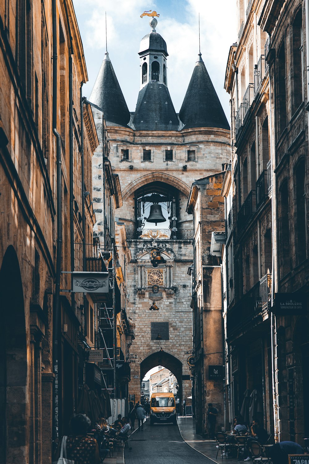 a narrow city street with a clock tower in the background