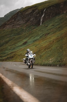 A motorcycle rider exploring a winding mountain road with lush greenery in the background.