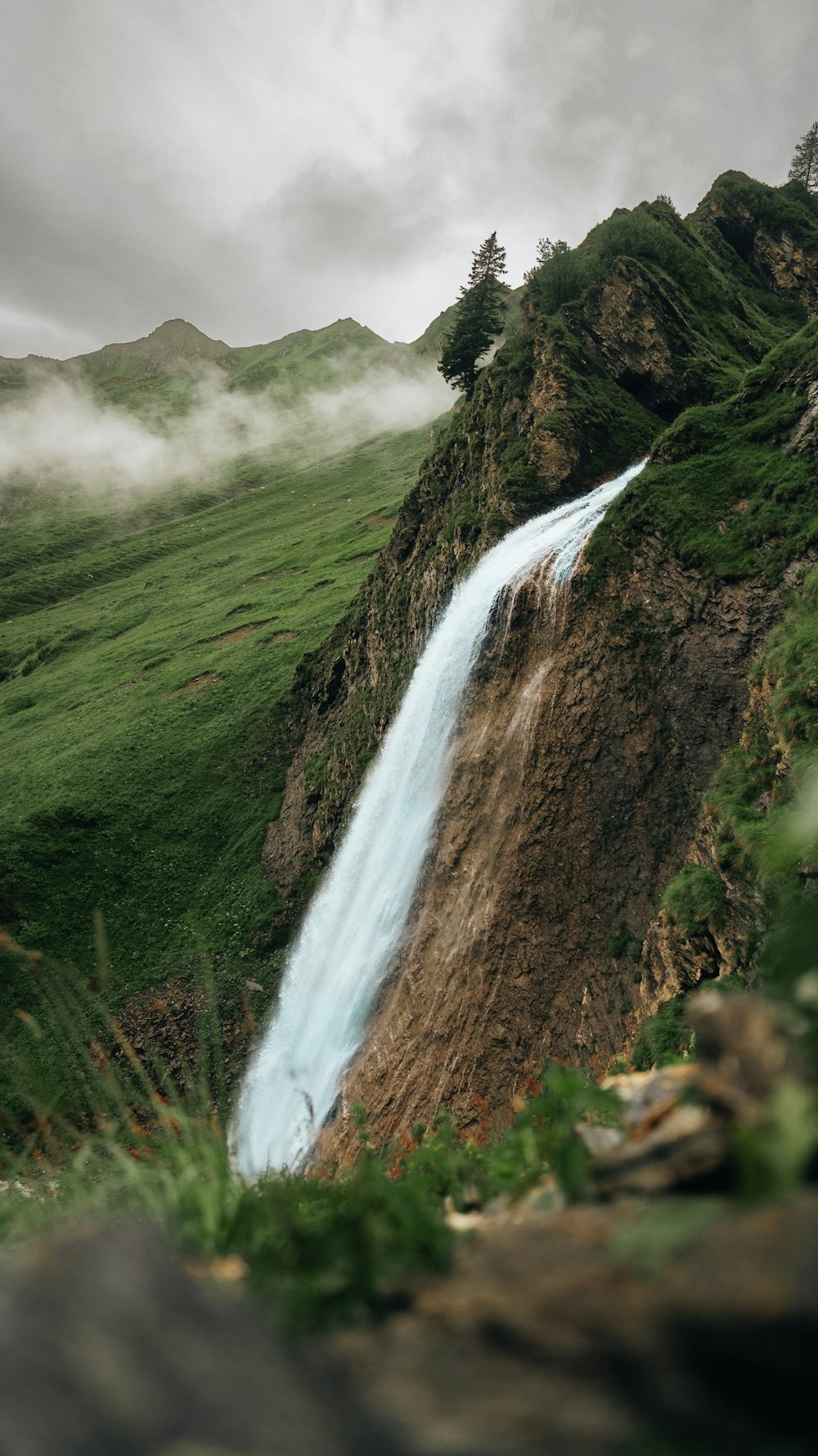 a waterfall in the middle of a lush green valley
