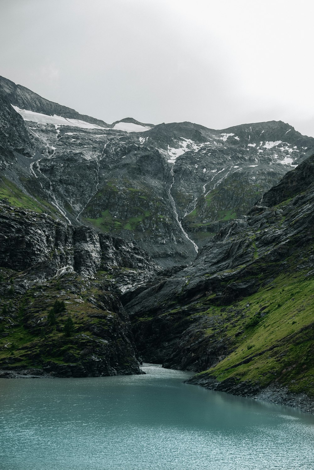 a body of water surrounded by mountains and grass