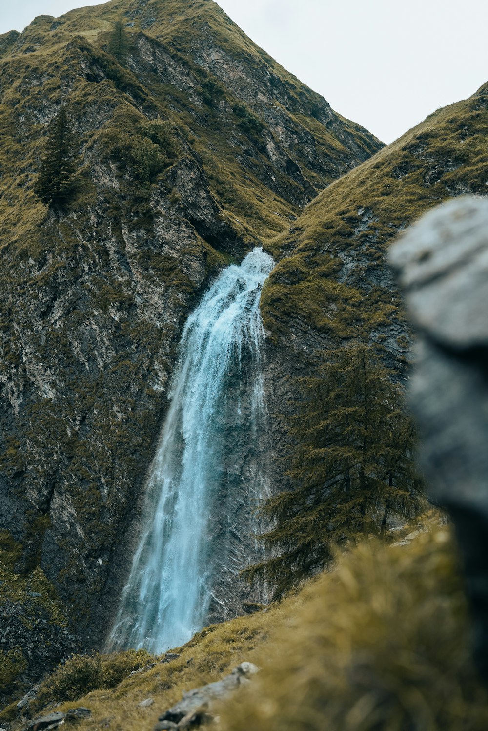 a wooden bench sitting in front of a waterfall