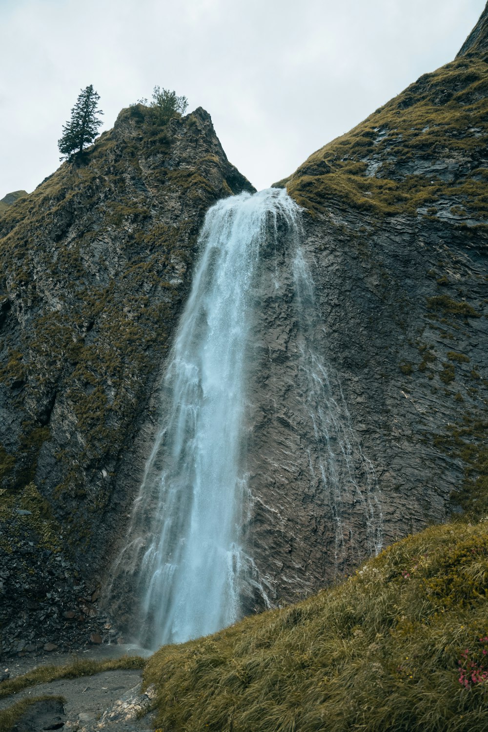 a tall waterfall is coming out of the side of a mountain