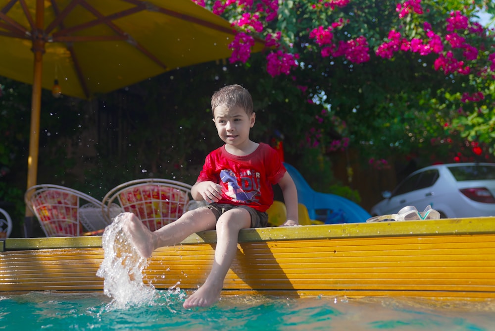 a young boy sitting on the edge of a swimming pool