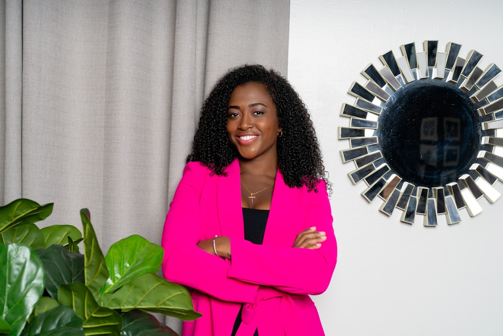 a woman standing in front of a mirror next to a plant