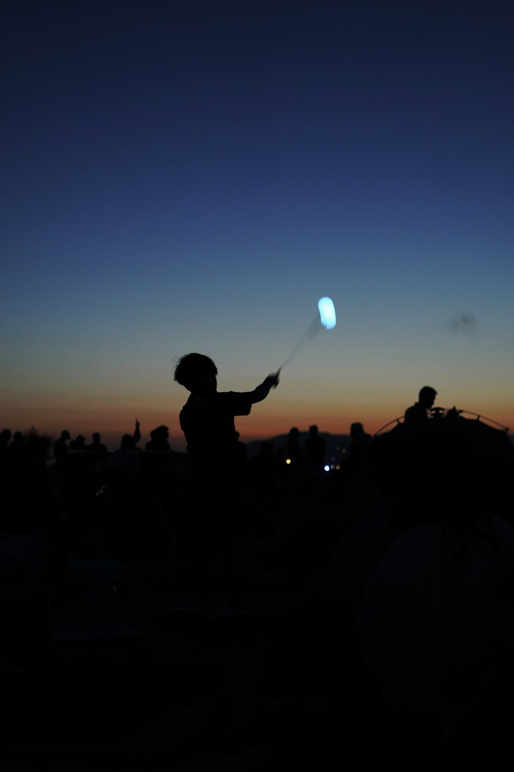 a silhouette of a person flying a kite at sunset
