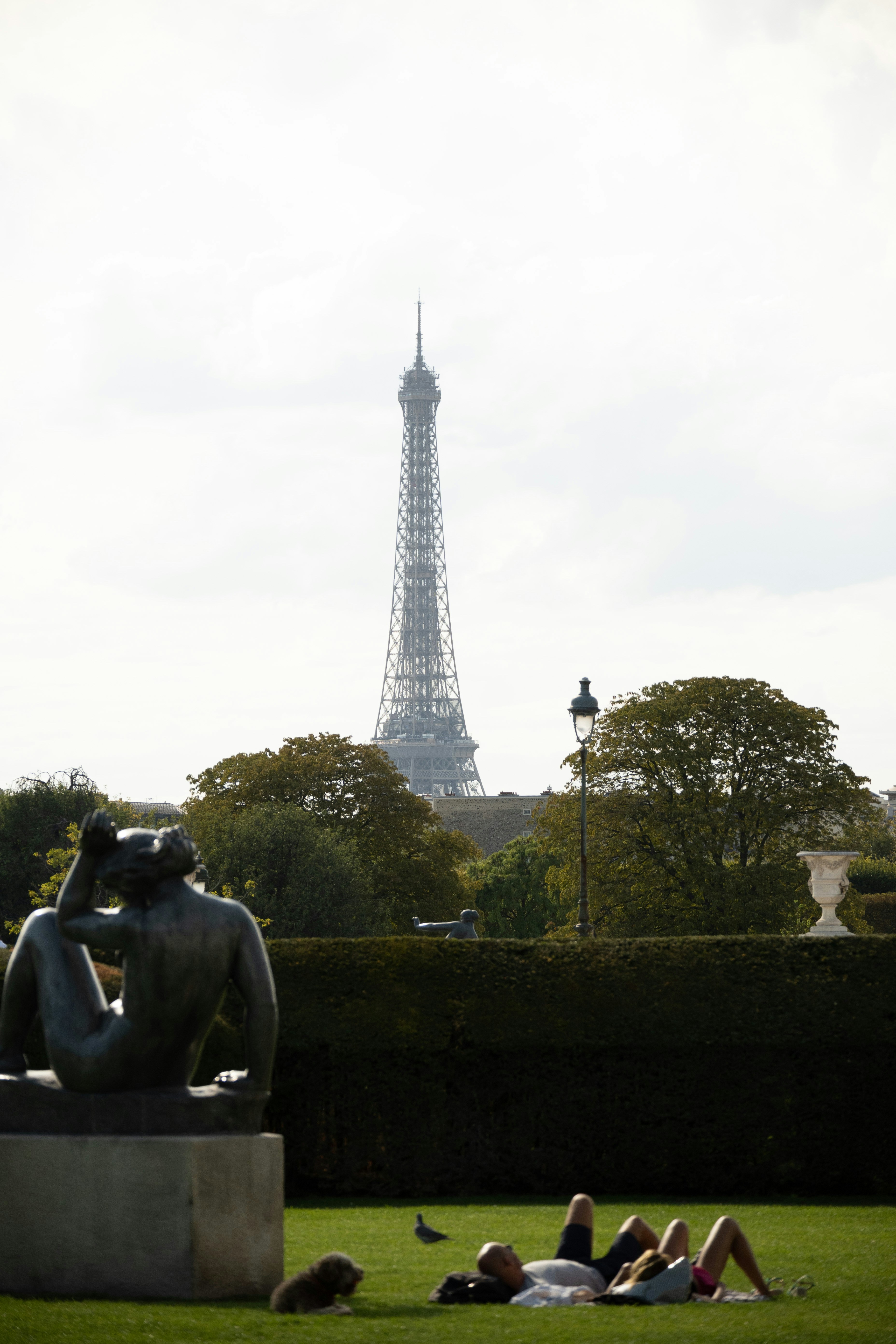 a group of people laying on the grass in front of the eiffel tower