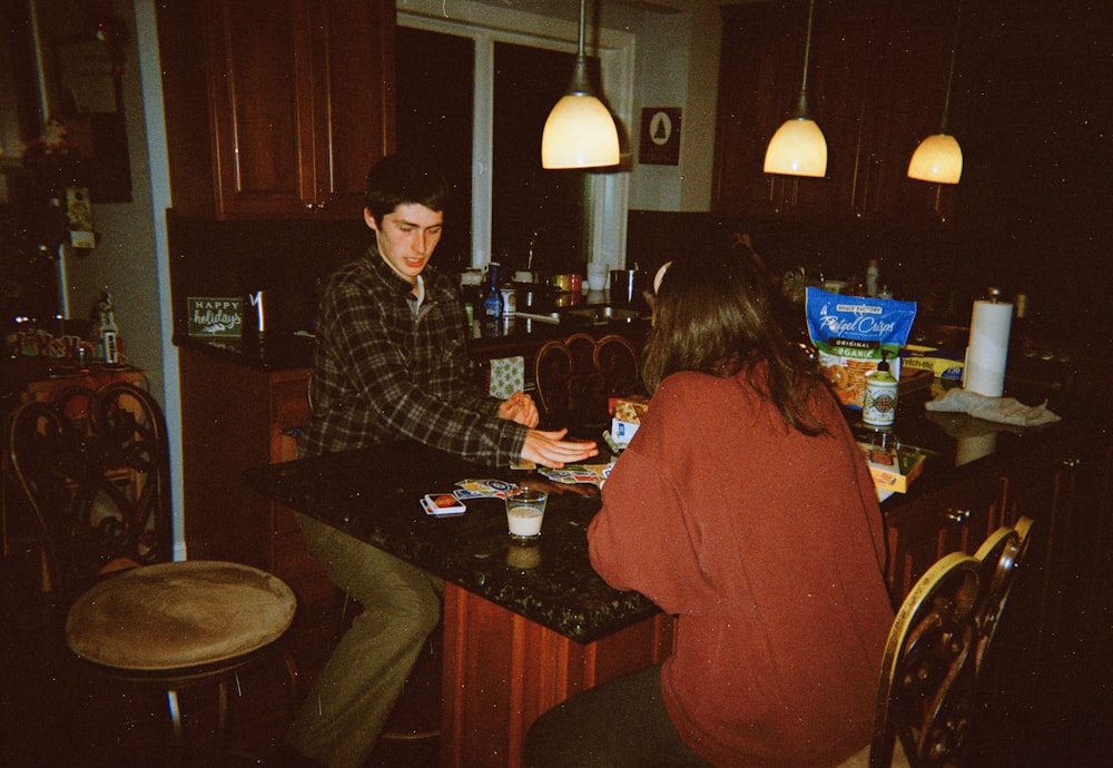 a man and a woman sitting at a kitchen counter