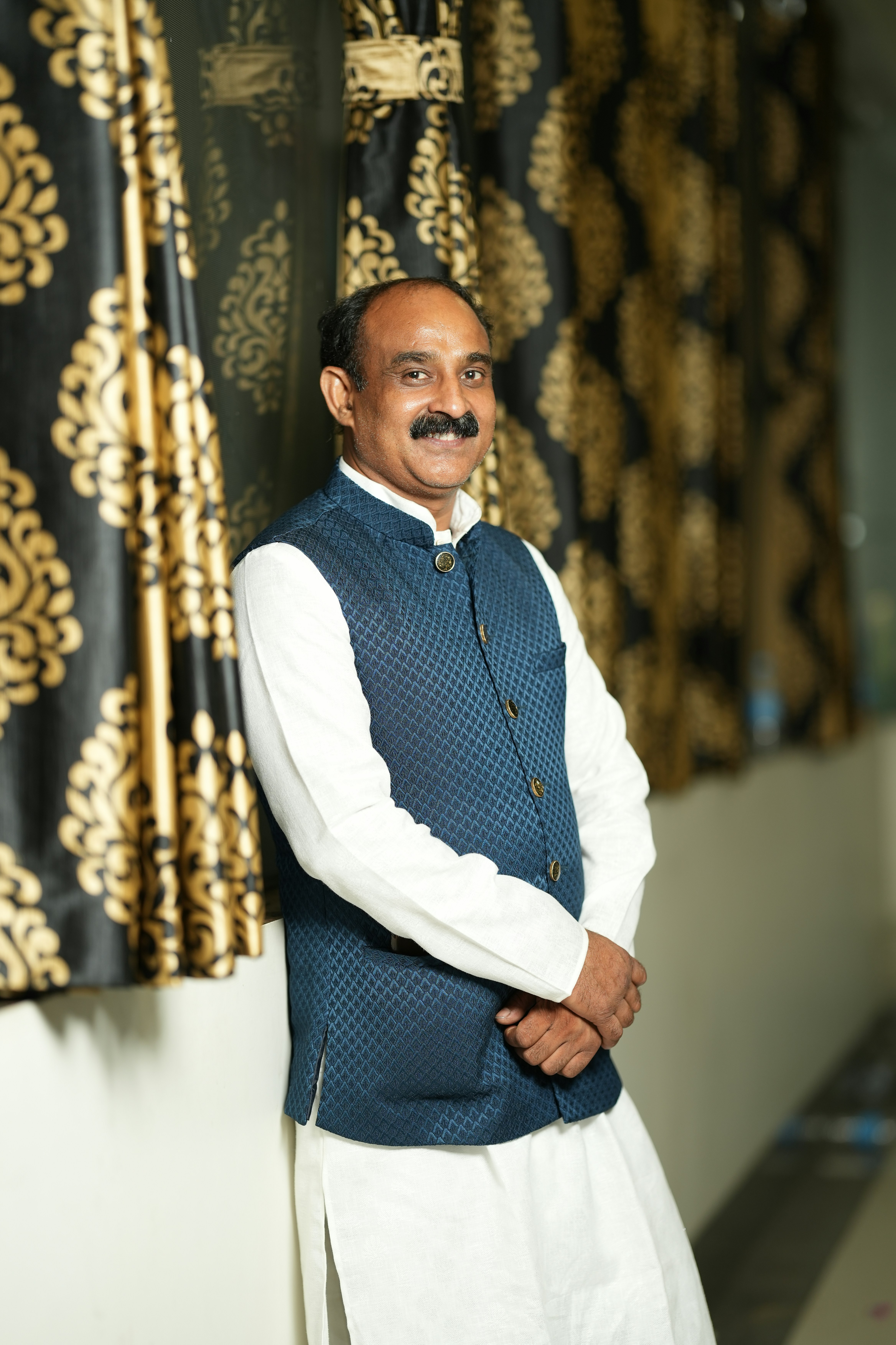 a man standing in front of a curtain with a moustache on his face