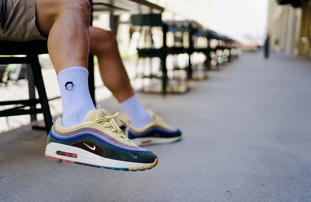 a man sitting on a bench wearing a pair of nike air max sneakers