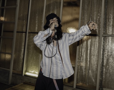 Close-up of the bald YouTuber holding a microphone with Japanese anime posters in the background.