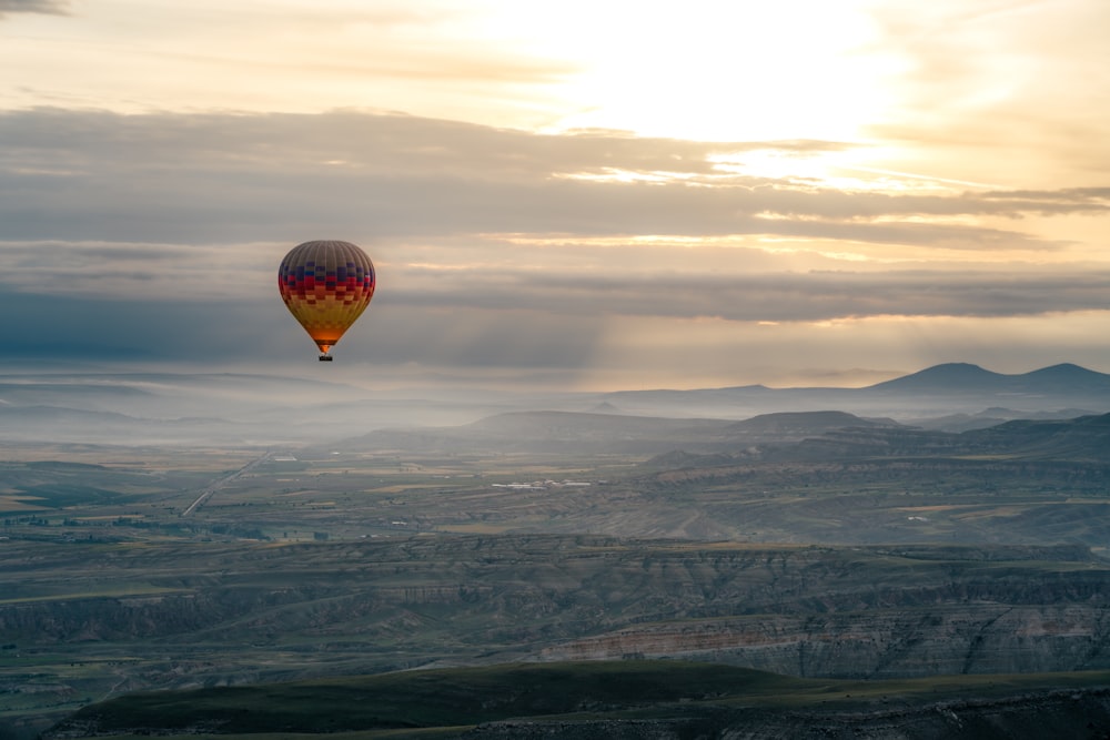 a hot air balloon flying over a valley
