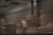 A collection of finished ceramic pieces drying on shelves bathed in soft natural light.