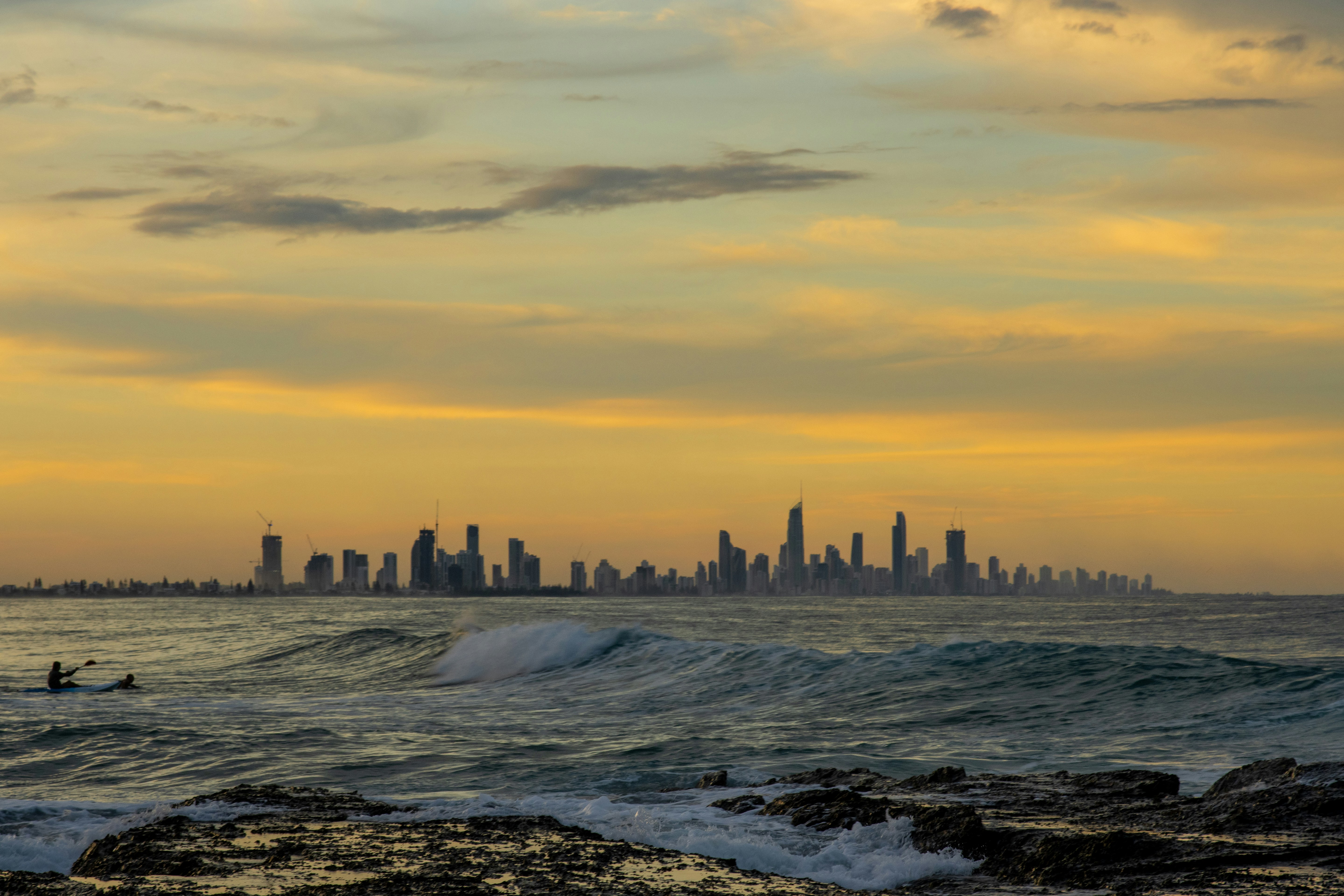 a surfer riding a wave in front of a city skyline