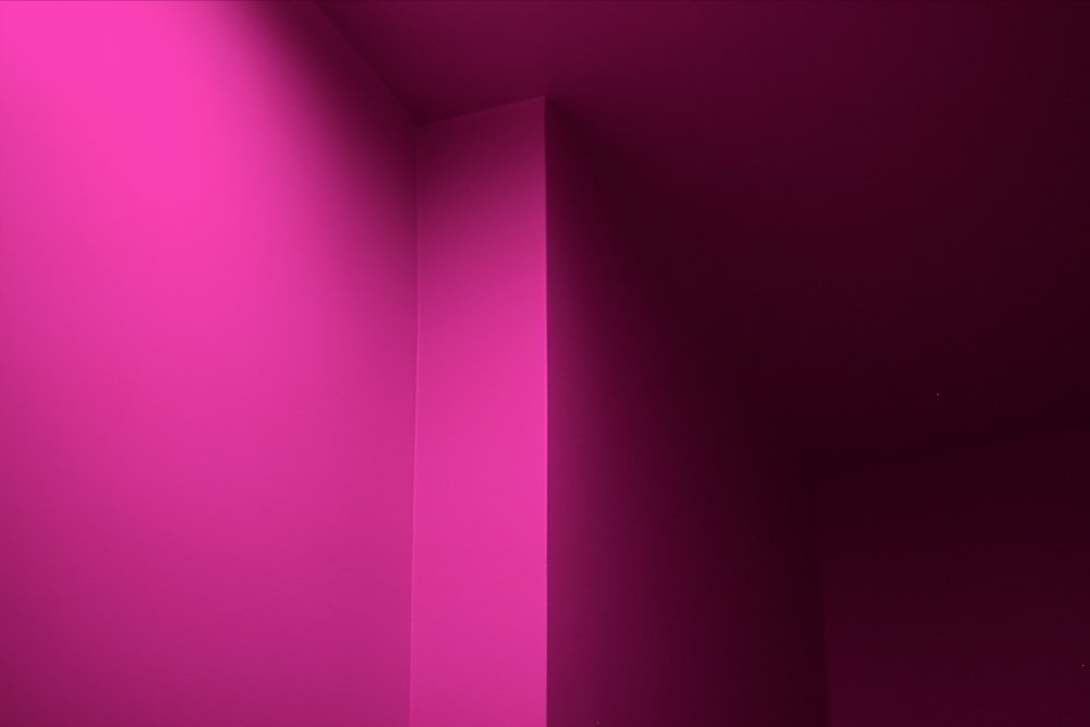 a room with a toilet and a pink wall