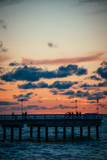 a group of people standing on a pier at sunset