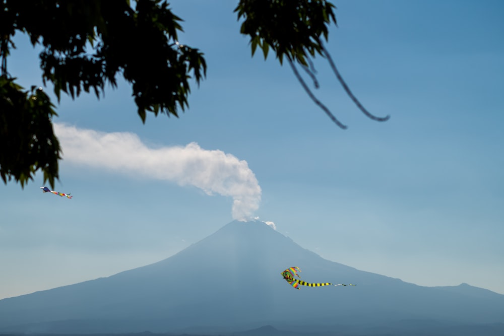 a kite flying in the sky with a mountain in the background