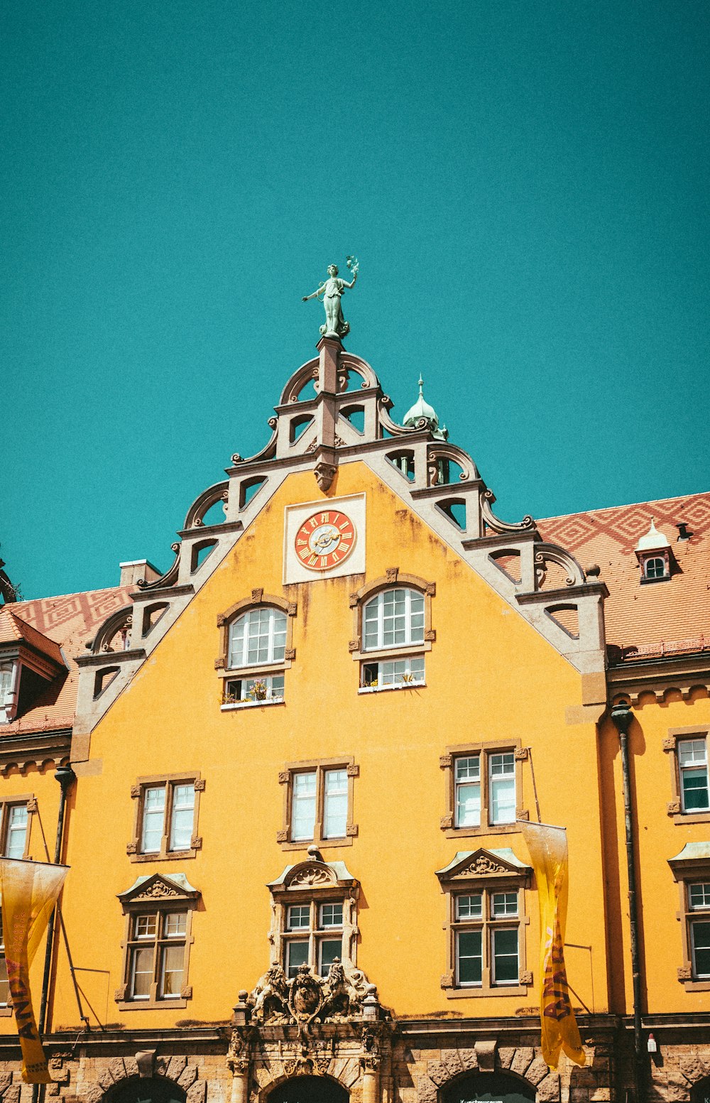 a tall yellow building with a clock on it's face