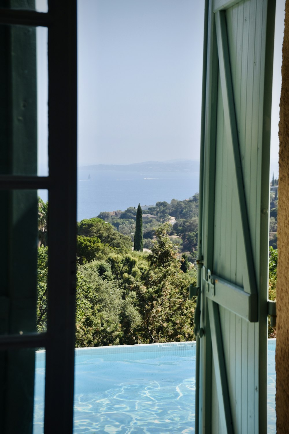 une porte ouverte menant à une piscine avec vue sur l’océan