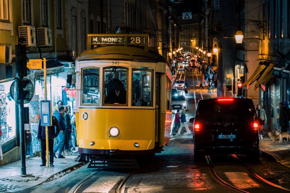 a yellow trolley car on a city street at night