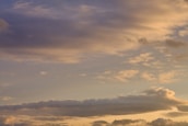Clouds spread across the sky with a soft gradient of colors ranging from light blues to warm oranges and yellows, typical of a sunset or sunrise.