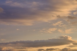 Clouds spread across the sky with a soft gradient of colors ranging from light blues to warm oranges and yellows, typical of a sunset or sunrise.