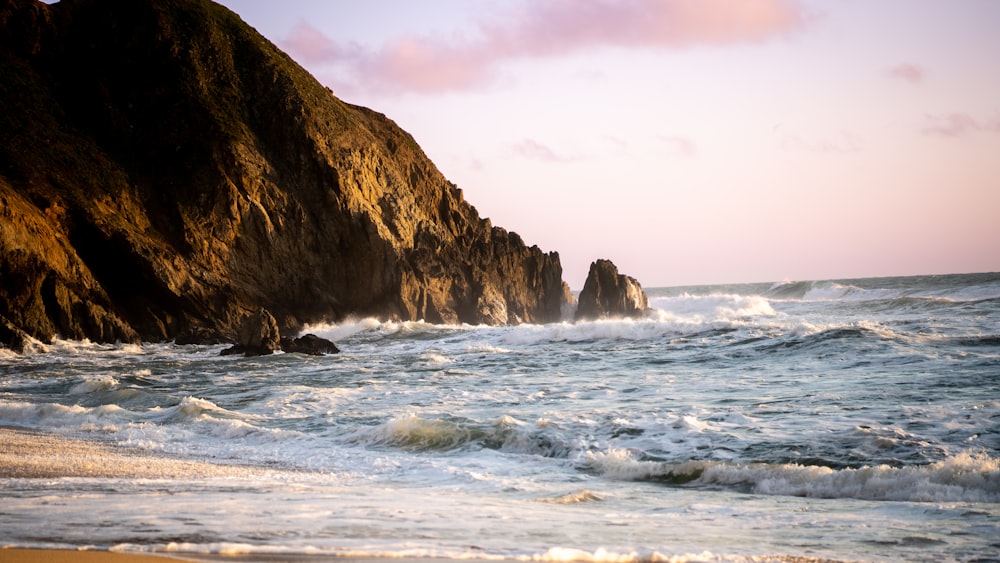 a beach with waves crashing against the rocks