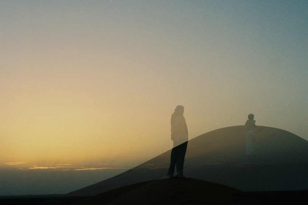 a couple of people standing on top of a hill