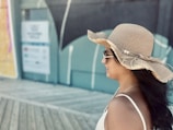 A model walking along the shoreline wearing a chic, clean-lined straw hat that catches the breeze.