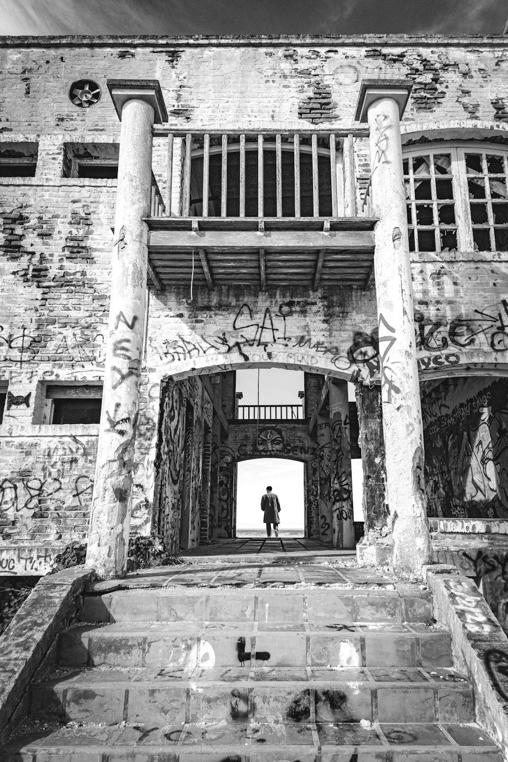 a black and white photo of a man standing in a doorway