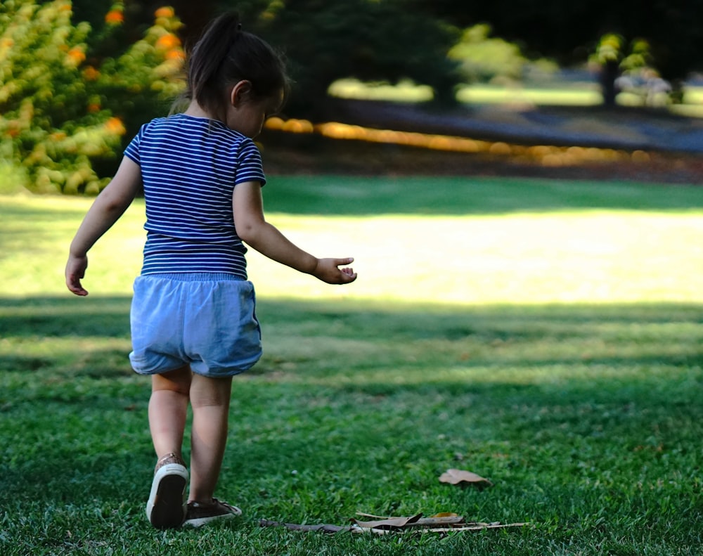 a little girl standing on top of a lush green field