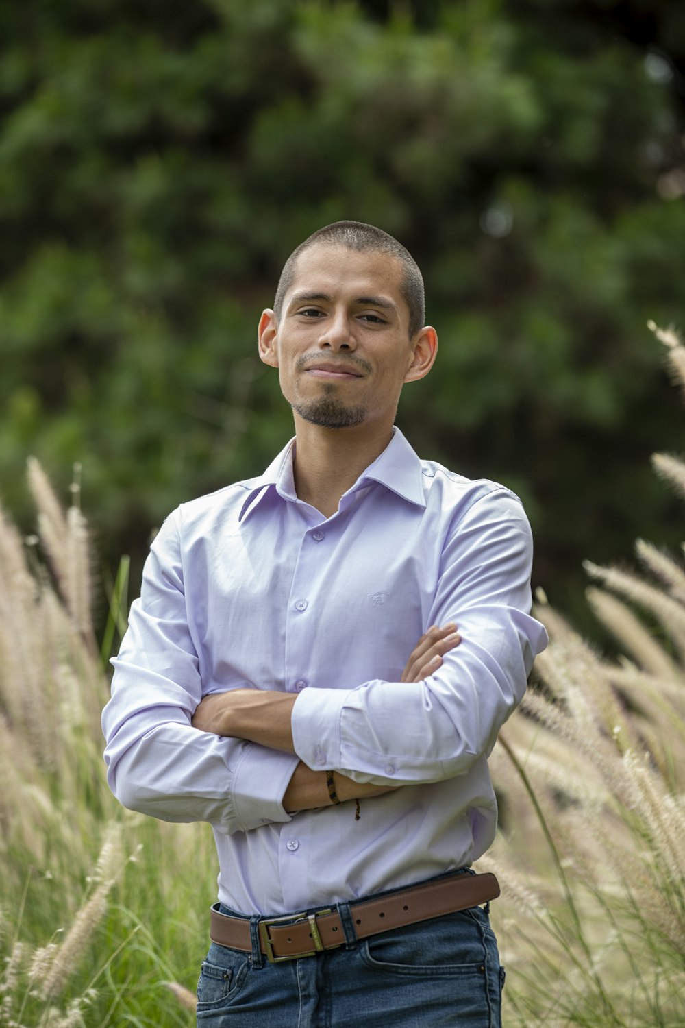 a man standing in a field with his arms crossed