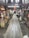 A wooden walkway leads through a rustic, indoor market area with various stalls selling souvenirs and local goods. The atmosphere is busy, with a few people visible in the distance. The market is housed in an older, wooden structure, adding a traditional charm to the setting.