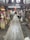 A wooden walkway leads through a rustic, indoor market area with various stalls selling souvenirs and local goods. The atmosphere is busy, with a few people visible in the distance. The market is housed in an older, wooden structure, adding a traditional charm to the setting.