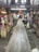 A wooden walkway leads through a rustic, indoor market area with various stalls selling souvenirs and local goods. The atmosphere is busy, with a few people visible in the distance. The market is housed in an older, wooden structure, adding a traditional charm to the setting.