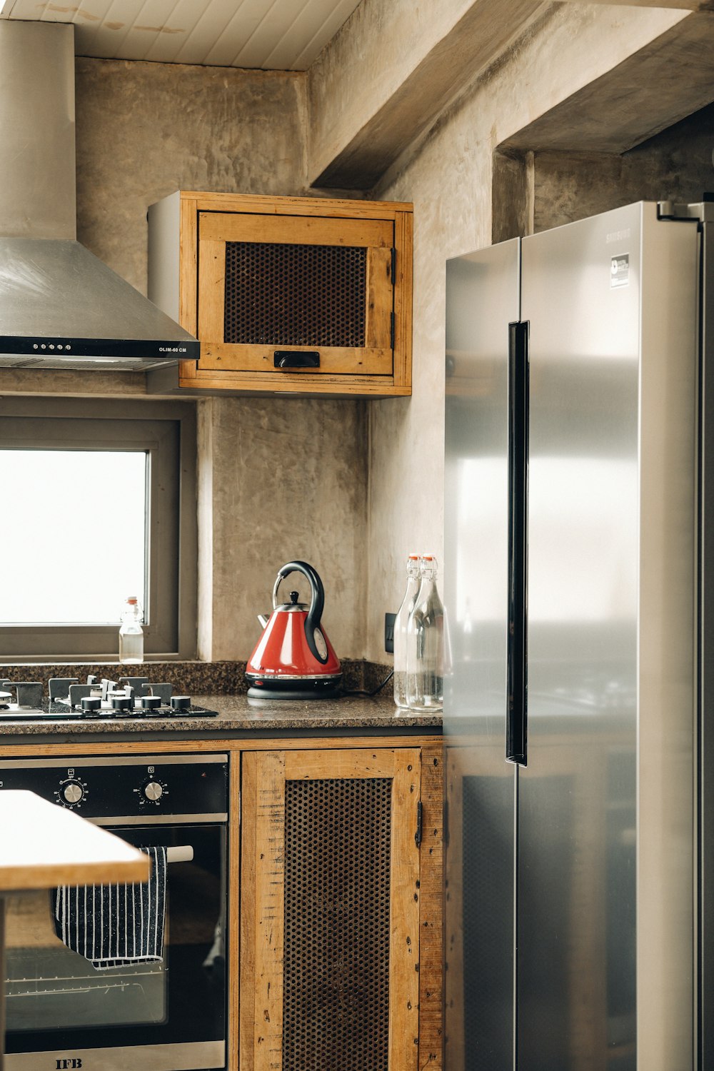 a kitchen with a stove, refrigerator and a kettle on the counter