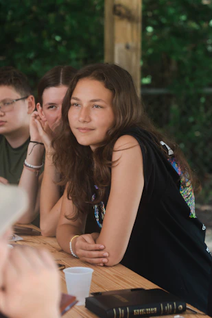 A group of diverse teens sitting together outdoors, engaged in thoughtful conversation and reflection.
