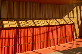 A cozy, modern minimalist room with warm orange accents and natural light streaming through a large window.