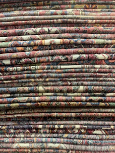 Stacks of neatly folded handloom rugs and cushions ready for export.