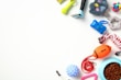 An assortment of pet toys and accessories arranged on a white background. Items include a rope chew toy, a blue feeding bowl filled with kibble, an orange football-shaped toy, a green spiky toy, a small rubber ball, a pair of grooming tools, and a colorful rubber knot ball.