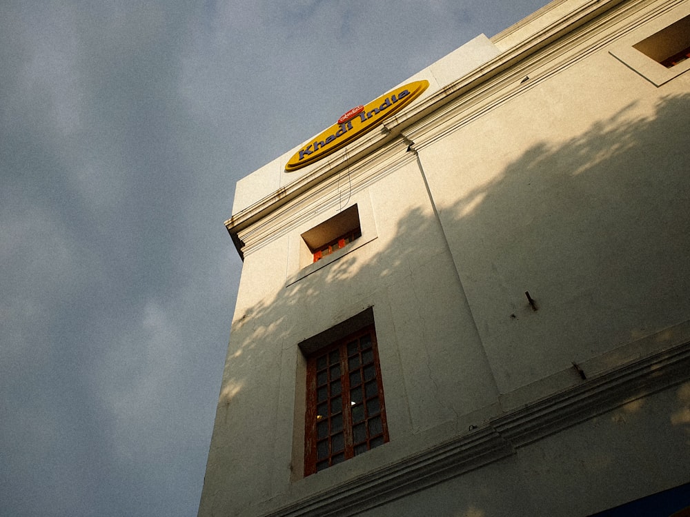 a tall white building with a yellow sign on top of it