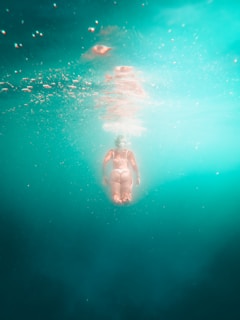 An instructor guiding a student through buoyancy control in a clear blue pool.