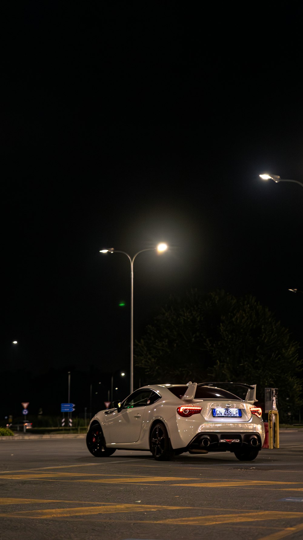 um carro esportivo branco estacionado em um estacionamento à noite