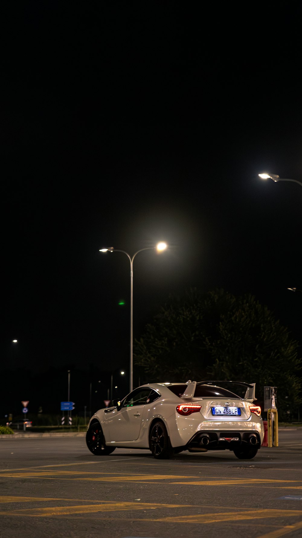 ein weißer Sportwagen, der nachts auf einem Parkplatz geparkt ist