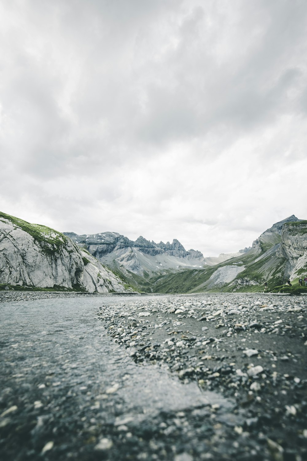 a body of water surrounded by mountains under a cloudy sky