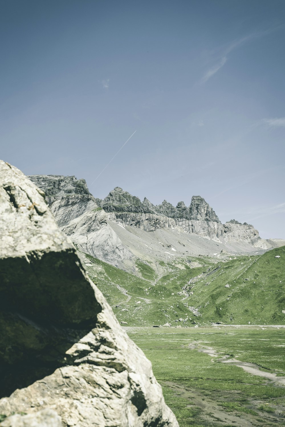 a man flying a kite on top of a lush green hillside