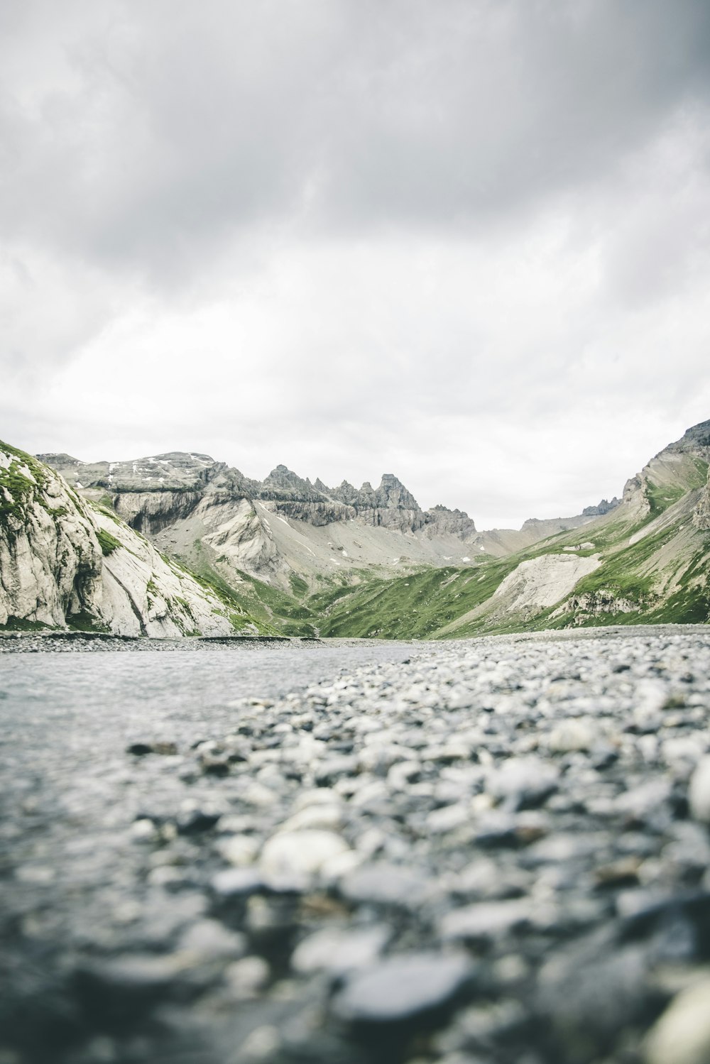 a body of water surrounded by mountains under a cloudy sky