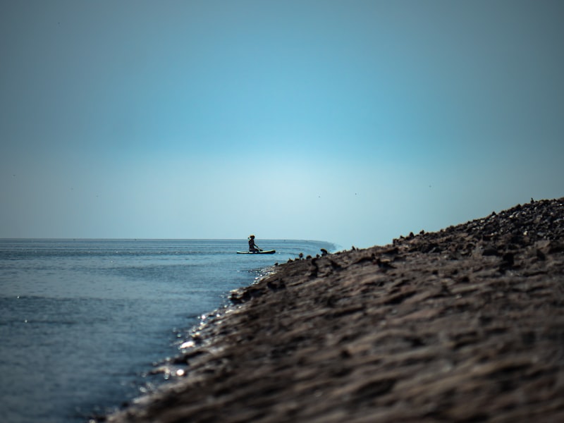 Person paddle boarding on calm blue water